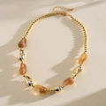 Vista dettagliata di perle irregolari in acrilico e oro su una collana alla moda - Grigio