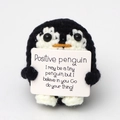 Detail of hand-knitted penguin doll holding a positive message card on white background - Black Penguin P Card