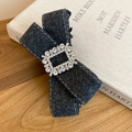 Detail of grey wool bow hair clip with sparkling rhinestone buckle on vintage book - Gray
