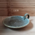 Detailed view of a 12cm speckled ceramic candle plate with handle on wooden texture - Kiln Glaze Green / 12cm