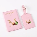 Close-up of pink PU leather passport holder and luggage tag with gold letter M and travel icons - Pink Letter M