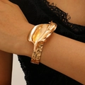 Goldener Blumenarmreif mit Hammerschlag-Metall-Design am Handgelenk des Models - Calla-Lilien-Armband (Gold)
