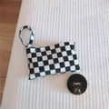 Detailed close-up of a black and white checkerboard knit mini bag on white bedding - Black & White Checkerboard