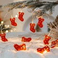 Christmas LED string lights with red cutout star stockings on snow-covered pine branches - Red Christmas Sock