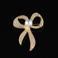 Elegante spilla a fiocco dorata con cristalli scintillanti e perla su sfondo nero - Stile B214