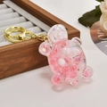 Cute pink turtle liquid glitter keychain with gold metal clasp on wooden tray - Nocturnal Pink
