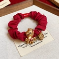 Vue macro du chouchou en satin rouge avec pendentif cheval doré et symbole porte-bonheur - 31# Elastique-Rouge-Cheval-Chance
