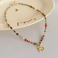 Detail of colorful beaded necklace featuring a golden elephant pendant on ceramic tray - Colorful