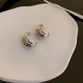 Macro shot of silver C-shaped earrings with hammered metal texture on white tray - Silver Crinkle