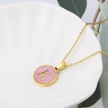 Golden necklace featuring a round pink shell pendant with a metallic letter K engraving - Pink-K