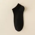 Men's solid black low cut cotton socks with ribbed elastic cuffs on leather background - One Size / Black