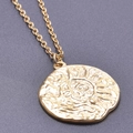 Macro shot of gold sun pendant with relief texture and polished stainless steel finish - Gold Necklace