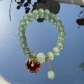 Green bead bracelet with golden metal accents and red floral pendant on reflective surface - S048-red Peace Lock Donglin Jade Beaded Bracelet #sz348