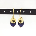 Macro shot of gold Tree of Life charm earrings with blue lapis lazuli stones on a stand - Deep Blue (Style 6)