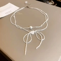 Detailed macro of a double-layered bow necklace with white beads and a heart charm - White-Double Layer