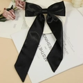Elegant black satin bow hair clip with long ribbons on a minimalist magazine background - Black