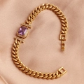 Close-up of gold geometric bracelet with purple zircon on luxurious rose gold satin - Purple Zirconia