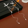 Detailed shot of a silver phoenix brooch with hanging pearls and tassels on black leather - Silver