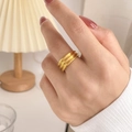 Close-up of golden multi-layer wave ring worn on finger with soft warm lighting - Three-ring Style