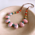 Dettaglio della collana etnica in ceramica con perline rosa e decori dipinti a mano - Stile Ceramica Ovale Dipinta a Mano