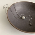 Minimalistische silberne Schlangenkette mit einzelner großer Perle in einer Keramikschale - Perlenball Schlangenkette Halskette