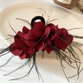 Primer plano de pinza para el pelo con flor roja oscura y elegantes plumas negras - Pinza de pelo de flor roja