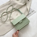 Mintgroene kleine vierkante crossbodytas met decoratieve ketting op een lichte blazer - Groen