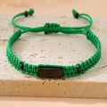 Detail of green woven bracelet with black stone centerpiece on travertine stone surface - Green (Black Plate)