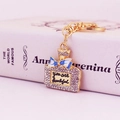 Golden perfume bottle keychain with rhinestones and blue bow on Anna Karenina book - Blue