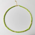 Detail of bohemian natural stone necklace with green beads and gold spacers on white background - Light Green Brown Spotted