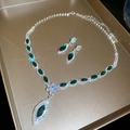 Vista macro del conjunto de joyas florales en plata con esmeraldas y diamantes brillantes - Set de Circonita Verde