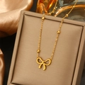 Goldene Halskette mit Schleifenanhänger und kleinen Perlen in einer Schmuckschatulle - 040