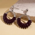 Detailed shot of vintage silver hoops with deep red leather wrap on a stone texture - Red