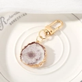 Macro detail of a resin keychain with real purple flower and wavy gold metal frame - Lavender Marigold