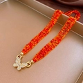 Detail of layered orange ceramic beads with a sparkling gold butterfly clasp - Orange-Red/Butterfly Clasp