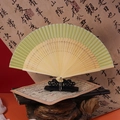 Chinese vintage folding fan with bamboo frame and green trim on a black display stand - 42 Square Rice Green