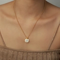 Elegante gouden ketting met witte schelphanger gedragen door een vrouwelijk model - Witte Schelphanger / Goud