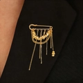 Detail of a gold safety pin brooch with hanging fringe chains on a black blazer lapel - KC Gold (Tassel Chain)
