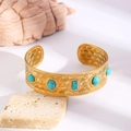 Detail of bohemian gold hammered metal cuff bracelet with turquoise stones on stone base - Turquoise Inlaid Hammered (1662) / 18k Gold