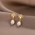 Gros plan de boucles d'oreilles coquillage doré avec perles d'eau douce blanches - Doré
