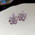 Macro shot of sparkling pink zircon flower earrings with silver prongs on white ceramic - Ear Buckle / Pink