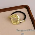 Elastisch haarstuk met een gouden metalen knoop en een zwart rekbaar haarelastiekje - Grote Knoop Goud