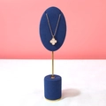 Rose gold necklace with white clover pendant displayed on dark blue velvet jewelry stand - Blue