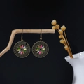 Detail of bohemian round hollow flower earrings with colorful enamel petals on a wood stand - Circular Flower Hollow Multicolor Enamel Style (E6341)