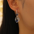 Detail of teardrop silver earrings with blue heart zircon stones worn by a model - Hollow Heart Blue Gem Dangle (11978)