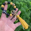Dettaglio bracciale leopardato con nappa gialla e croce nera in silicone con Jesus - Giallo + Leopardo