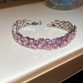 Close-up of sparkling pink pear-cut zircon stones set in a silver clasp bracelet - Pink
