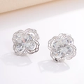 Macro shot of silver geometric flower earrings with sparkling zircon stones on a white surface - Flower