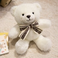 Weißer Plüsch-Teddybär mit brauner Glitzerschleife auf weichem Teppich zu Hause - Weißer Krawattenstil