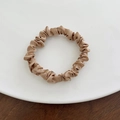 Coletero de satén champán con textura plisada en un plato de cerámica blanca y madera - Pequeño / Café Claro